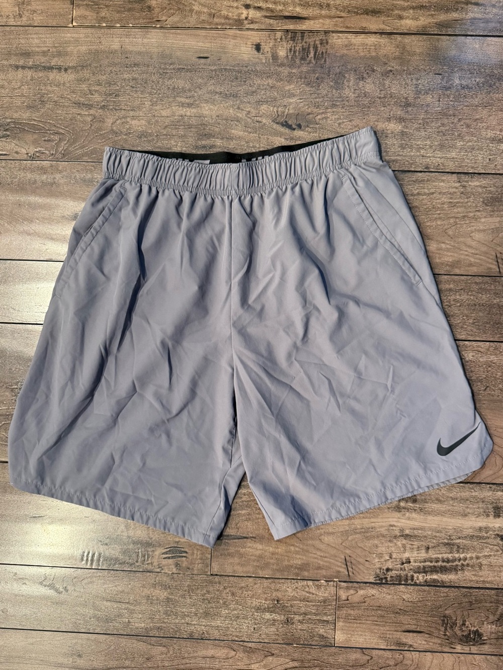 Nike Men’s Dri Fit Shorts in Light Gray with Black Swoosh and pockets.